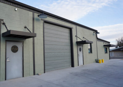 Green building exterior from front, featuring door with awning.